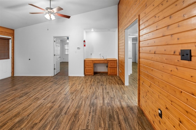 interior space featuring vaulted ceiling, dark wood-type flooring, wood walls, and baseboards