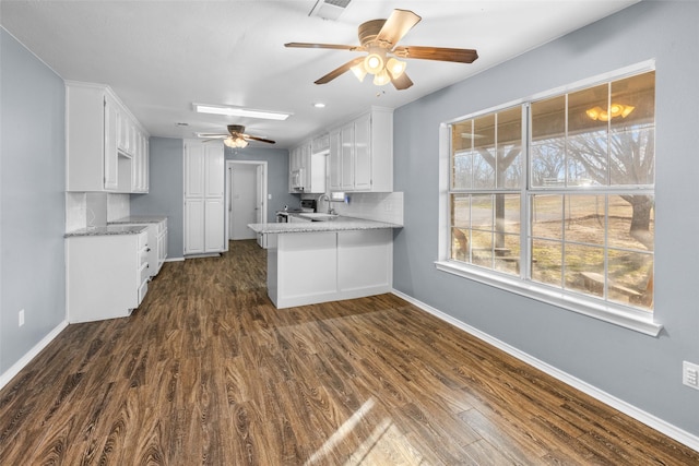 kitchen featuring a peninsula, dark wood-style floors, and white cabinetry