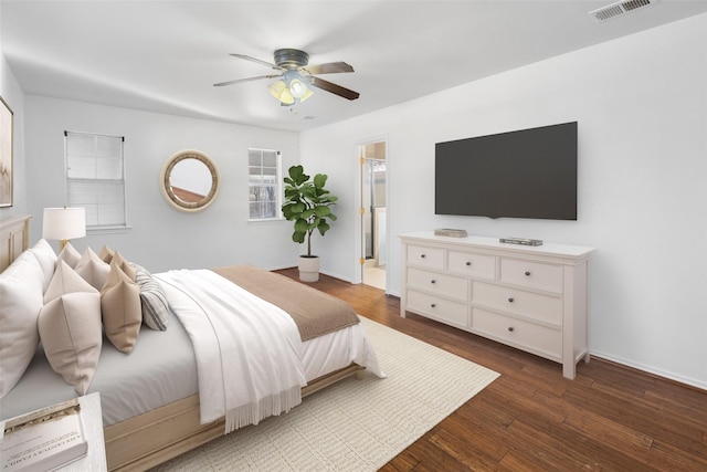 bedroom featuring ensuite bathroom, dark wood-type flooring, visible vents, baseboards, and a ceiling fan