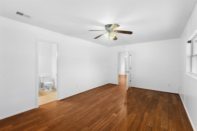 spare room with baseboards, wood finished floors, visible vents, and a ceiling fan