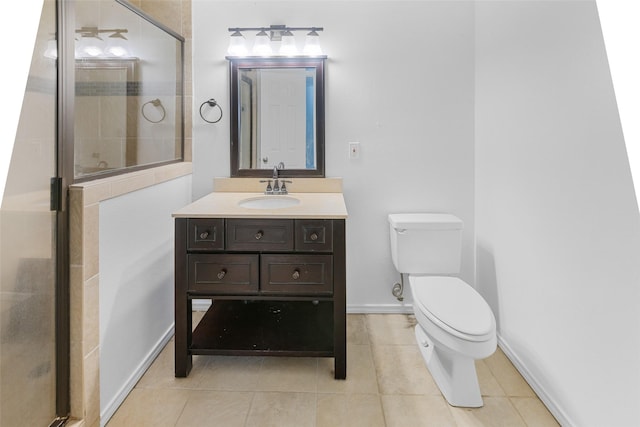 bathroom with toilet, a shower stall, vanity, baseboards, and tile patterned floors