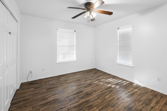 empty room with dark wood-style floors, baseboards, and a ceiling fan