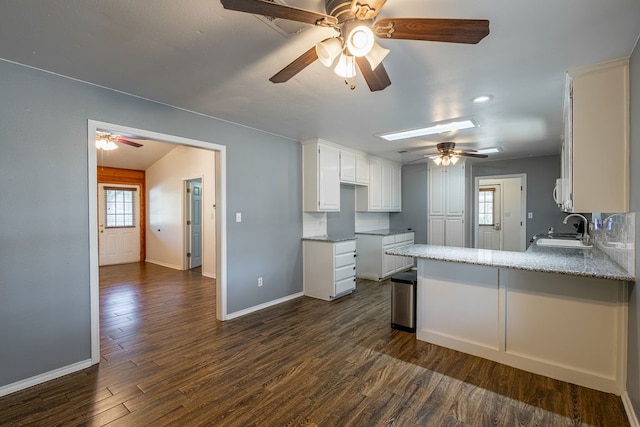 kitchen with kitchen peninsula, dark hardwood / wood-style flooring, sink, and white cabinets