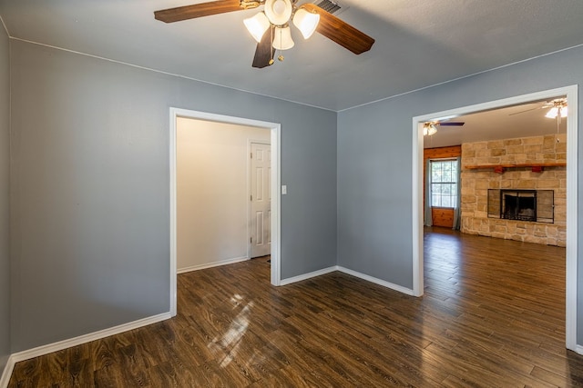 spare room with ceiling fan, a fireplace, and dark hardwood / wood-style floors