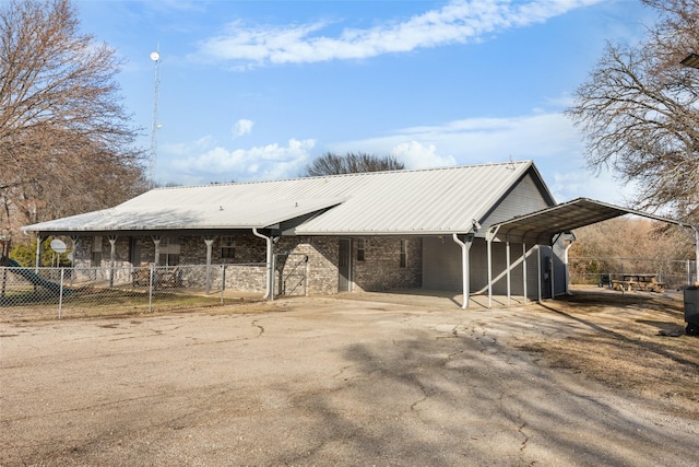 view of side of home with a carport, metal roof, and driveway