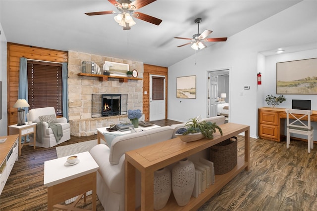 living room featuring lofted ceiling, a stone fireplace, dark wood finished floors, and a ceiling fan