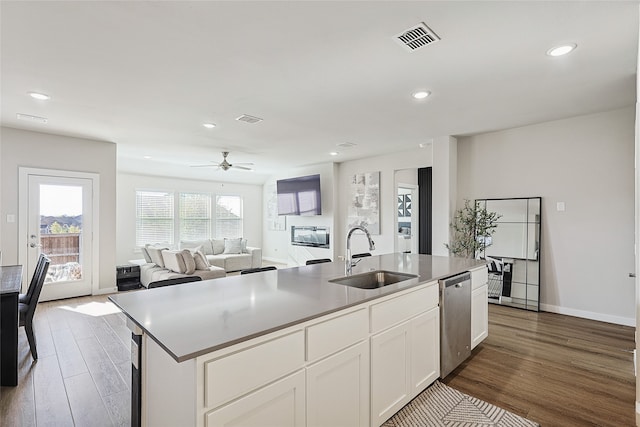 kitchen with sink, dark hardwood / wood-style flooring, white cabinetry, stainless steel dishwasher, and a kitchen island with sink