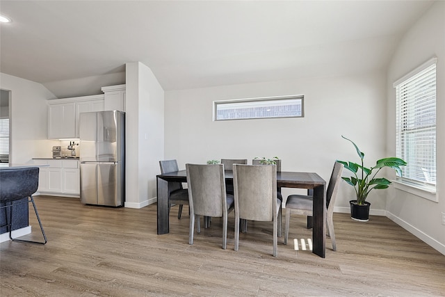 dining area with light hardwood / wood-style flooring and vaulted ceiling