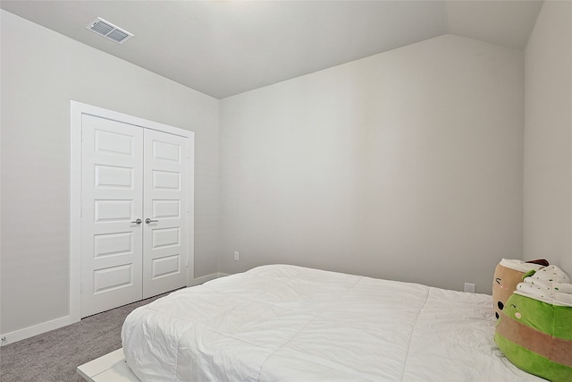 bedroom featuring a closet, lofted ceiling, and carpet