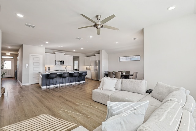 living room featuring ceiling fan and light hardwood / wood-style flooring