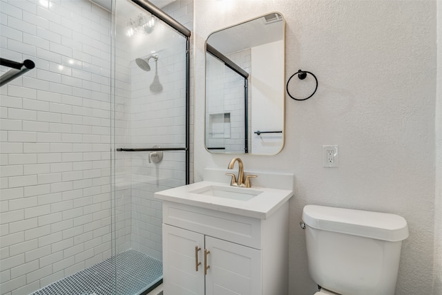 bathroom featuring toilet, vanity, and a shower with shower door