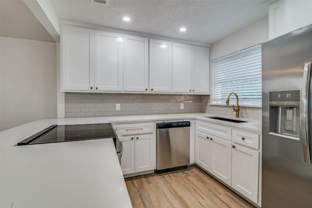 kitchen featuring white cabinets, a textured ceiling, stainless steel appliances, and sink