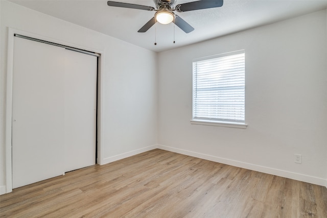 unfurnished bedroom with light wood-type flooring, ceiling fan, and a closet