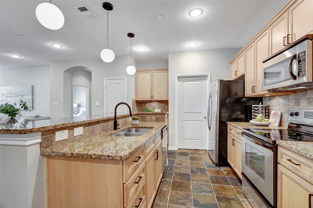 kitchen with tasteful backsplash, light brown cabinets, appliances with stainless steel finishes, and decorative light fixtures