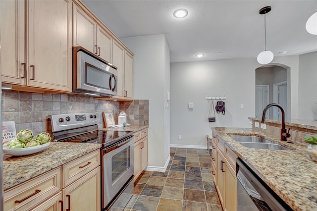 kitchen featuring stainless steel appliances, hanging light fixtures, sink, tasteful backsplash, and light brown cabinetry