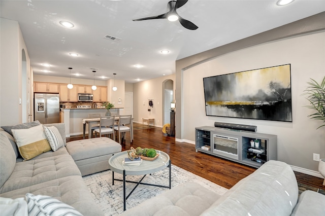 living room with dark wood-type flooring and ceiling fan