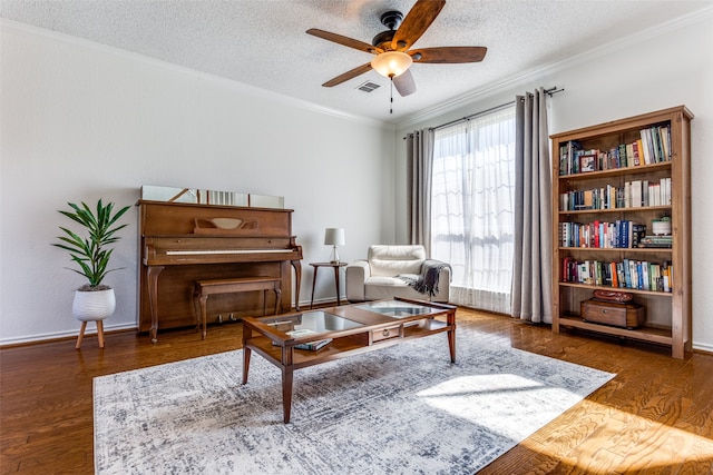 living area with ornamental molding, a textured ceiling, and dark wood-type flooring