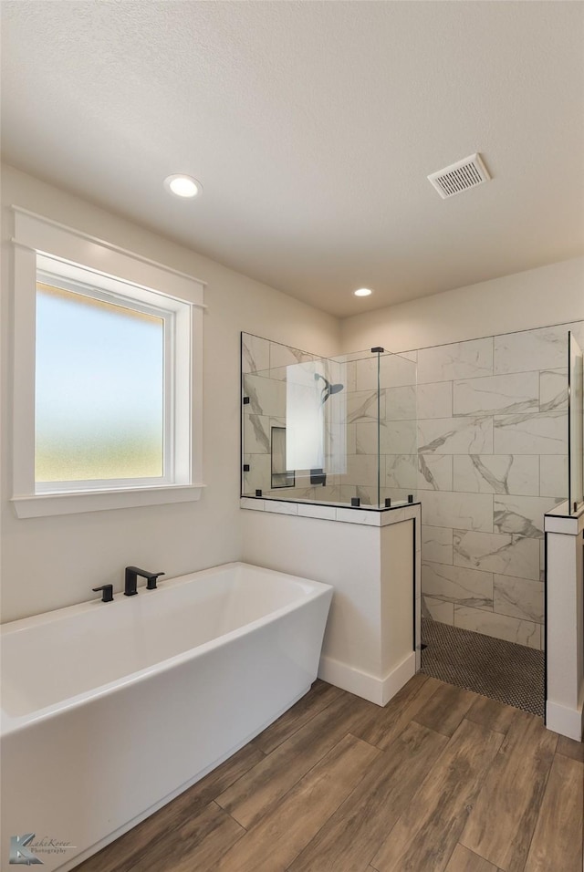 bathroom featuring plus walk in shower and hardwood / wood-style floors