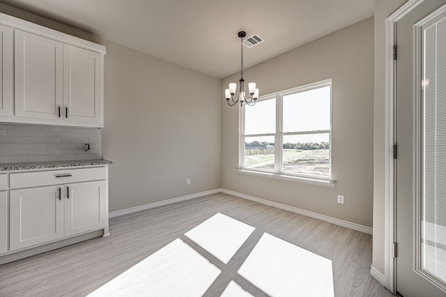 unfurnished dining area featuring a chandelier and light hardwood / wood-style flooring