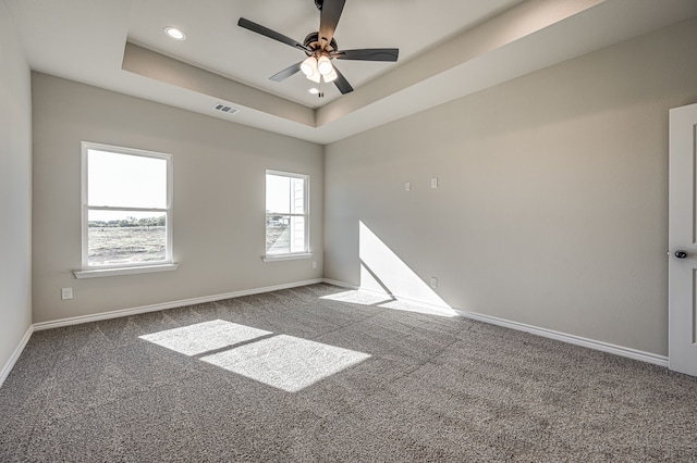 carpeted spare room with ceiling fan and a raised ceiling