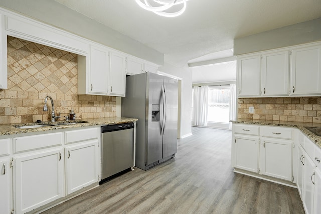 kitchen featuring white cabinets, appliances with stainless steel finishes, light wood-type flooring, and decorative backsplash