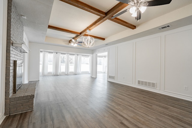 unfurnished living room with a brick fireplace, beamed ceiling, ceiling fan with notable chandelier, and dark hardwood / wood-style floors