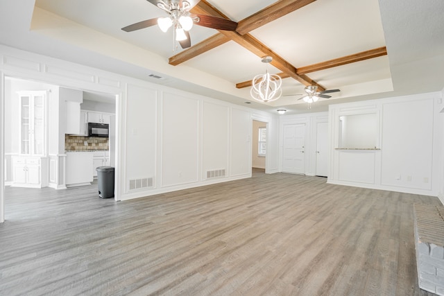 unfurnished living room with ceiling fan, a tray ceiling, and light hardwood / wood-style floors