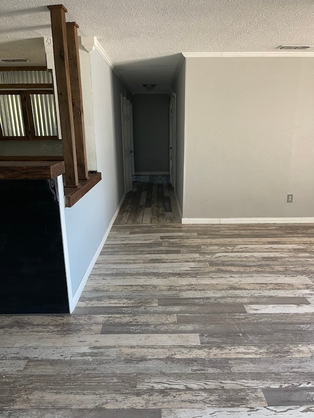 hallway with ornamental molding, hardwood / wood-style floors, and a textured ceiling