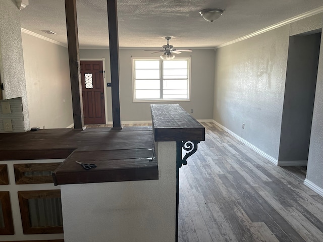 interior space featuring wood-type flooring, ornamental molding, a textured ceiling, and ceiling fan