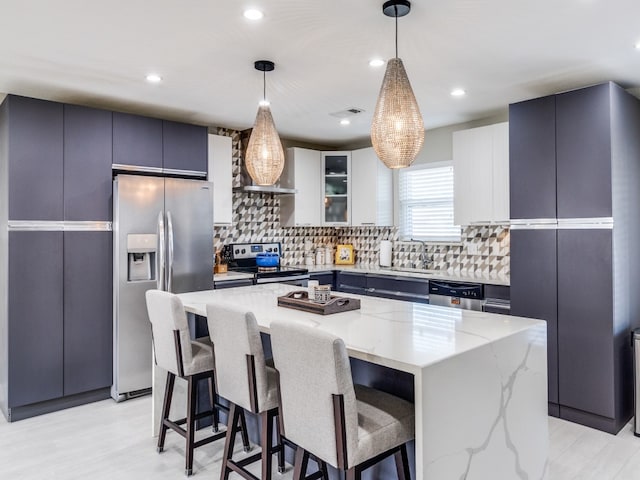 kitchen with stainless steel fridge, a kitchen island, pendant lighting, light hardwood / wood-style floors, and white cabinets