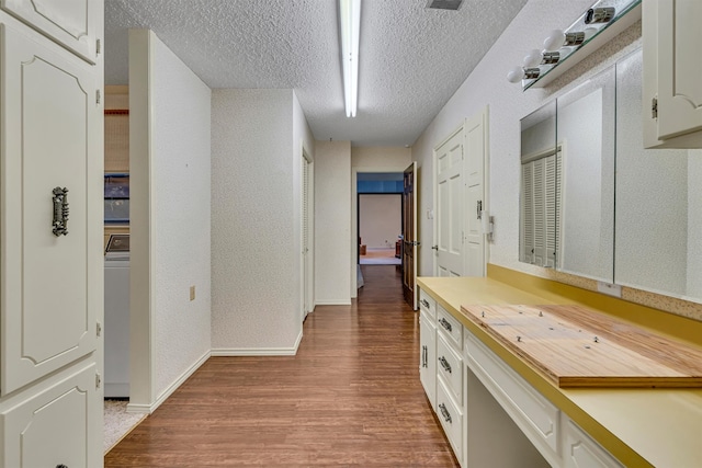 corridor featuring light hardwood / wood-style flooring, washer / clothes dryer, and a textured ceiling