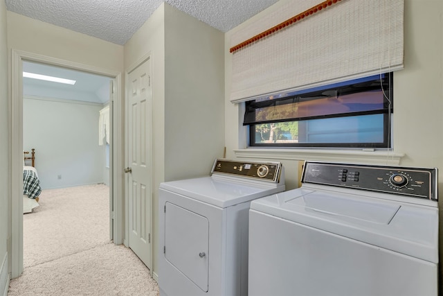 laundry area with light carpet, independent washer and dryer, and a textured ceiling