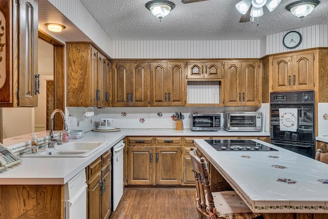 kitchen with black appliances, a textured ceiling, dark hardwood / wood-style flooring, sink, and tile countertops