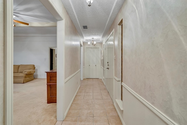 hallway with a textured ceiling and light carpet