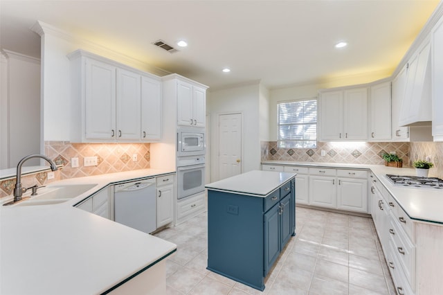 kitchen with white appliances, blue cabinets, sink, white cabinets, and a kitchen island