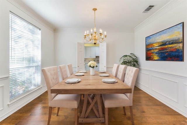 dining area with dark hardwood / wood-style flooring, crown molding, and a chandelier