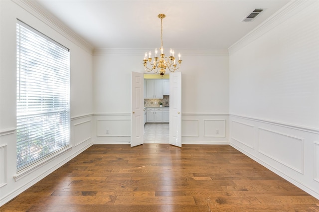 unfurnished dining area with ornamental molding, dark hardwood / wood-style flooring, and a notable chandelier