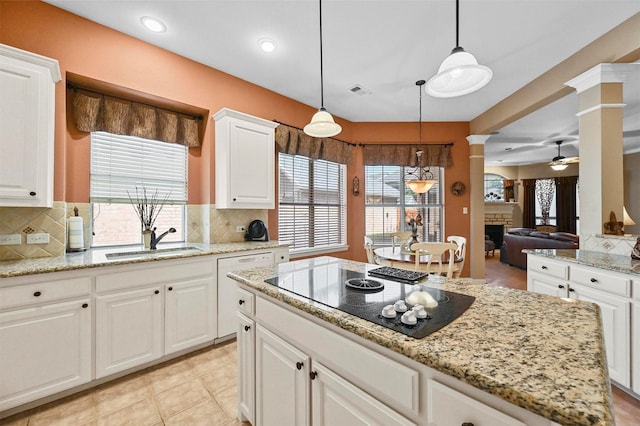 kitchen featuring pendant lighting, sink, white cabinets, black electric cooktop, and ornate columns