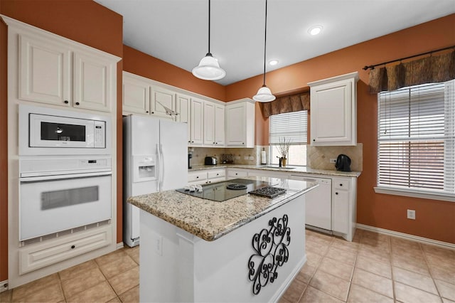 kitchen with light stone counters, a center island, pendant lighting, white appliances, and white cabinets