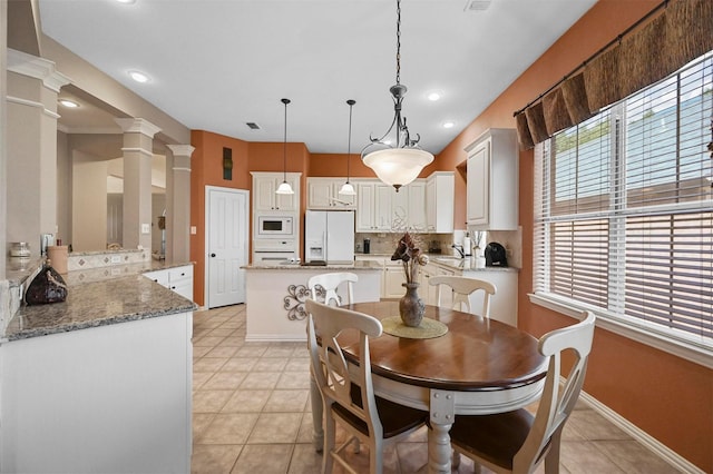 dining room featuring light tile patterned floors, decorative columns, and sink