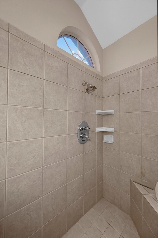 bathroom featuring lofted ceiling and tiled shower