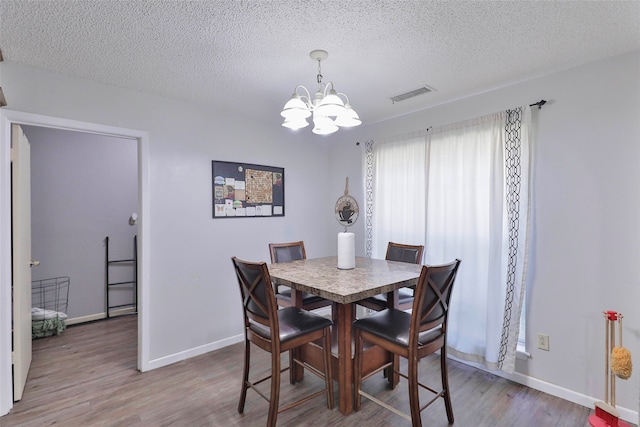 dining room with hardwood / wood-style flooring, a notable chandelier, and a textured ceiling