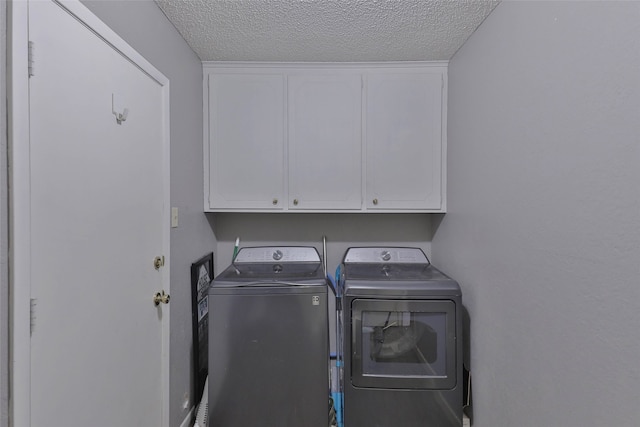 laundry area with cabinets, separate washer and dryer, and a textured ceiling