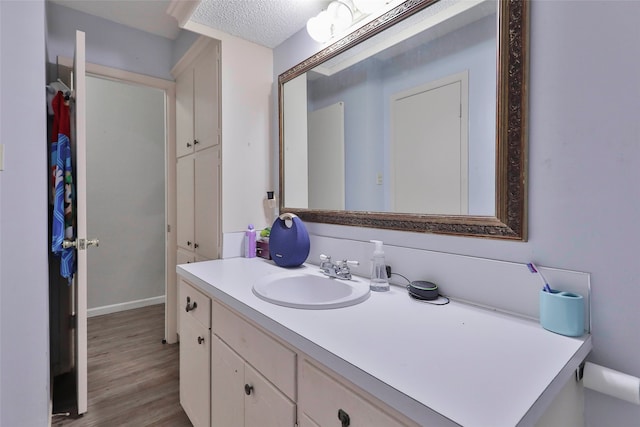 bathroom featuring vanity, wood-type flooring, and a textured ceiling