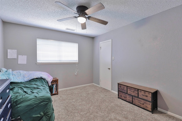 bedroom with ceiling fan, light colored carpet, and a textured ceiling