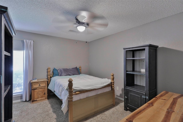 bedroom with light colored carpet, a textured ceiling, and ceiling fan