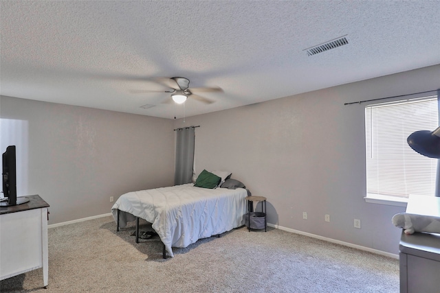 bedroom featuring ceiling fan, light colored carpet, and a textured ceiling