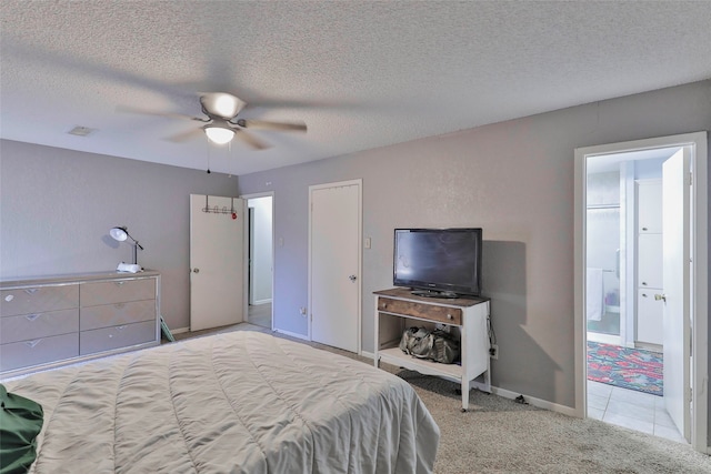 carpeted bedroom with ceiling fan, ensuite bath, and a textured ceiling