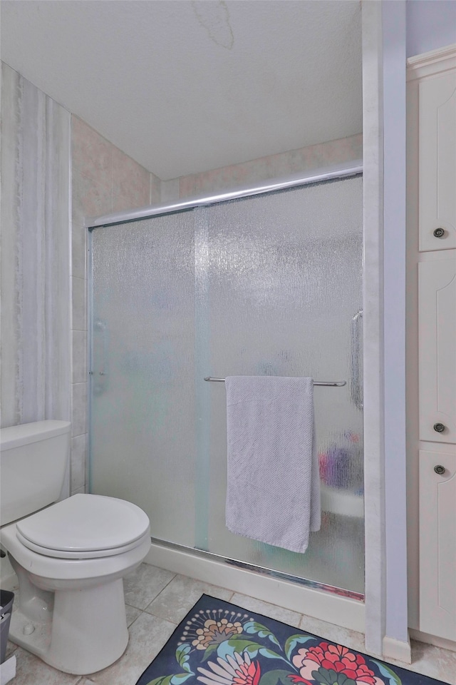 bathroom with toilet, an enclosed shower, and tile patterned floors