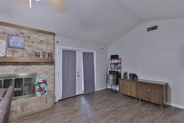 interior space featuring a brick fireplace, dark wood-type flooring, and vaulted ceiling